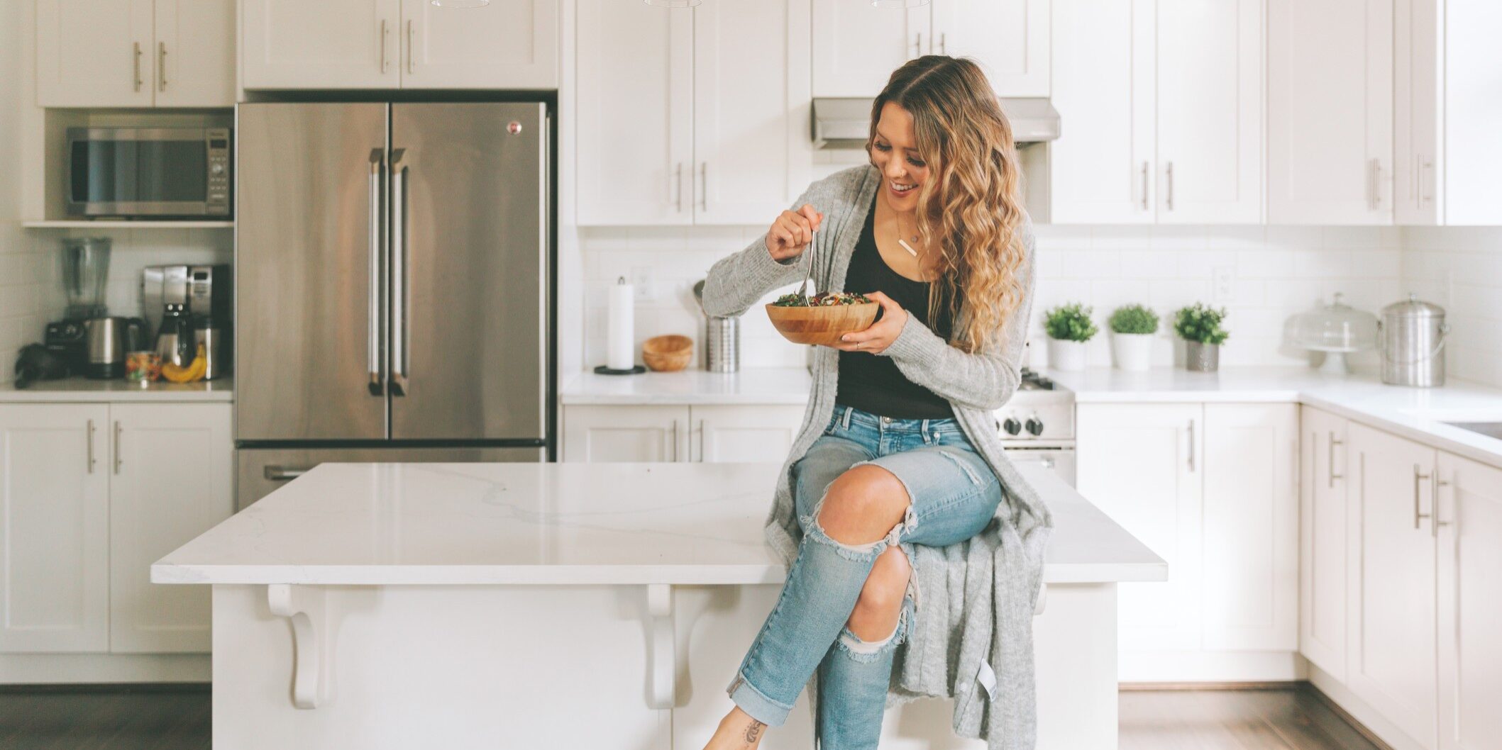 a-woman-eating-a-salad-while-sitting-on-the-kitchen-counter_t20_xR0peB